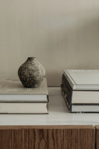Livros sobre uma mesa e um pequeno vaso sem flores sobre a pilha de dois livros